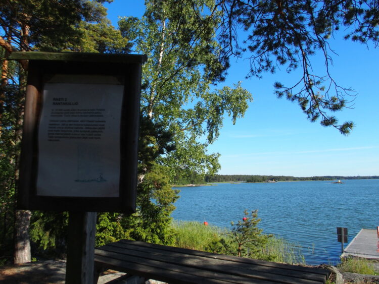 A view to sea from Reksaari's nature path with an informative sign in the foreground.