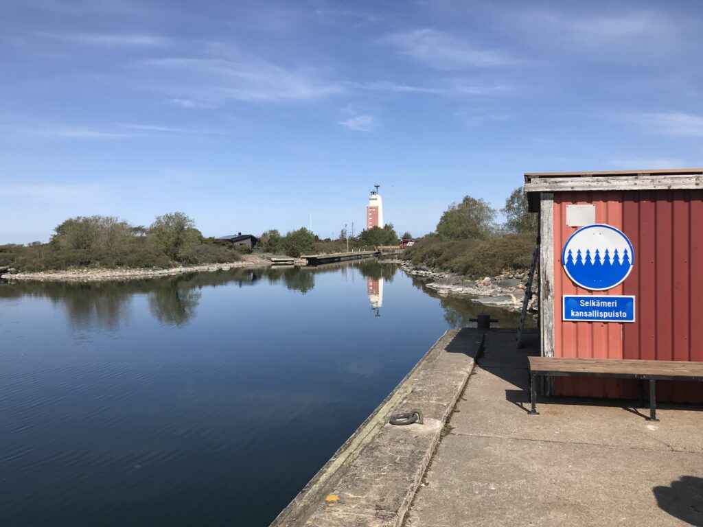 Bothnia Sea National Park sign in Kylmäpihlaja. Lighthouse on the background.