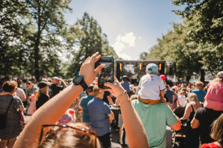 A person taking a picture at a crowd with a smartphone.