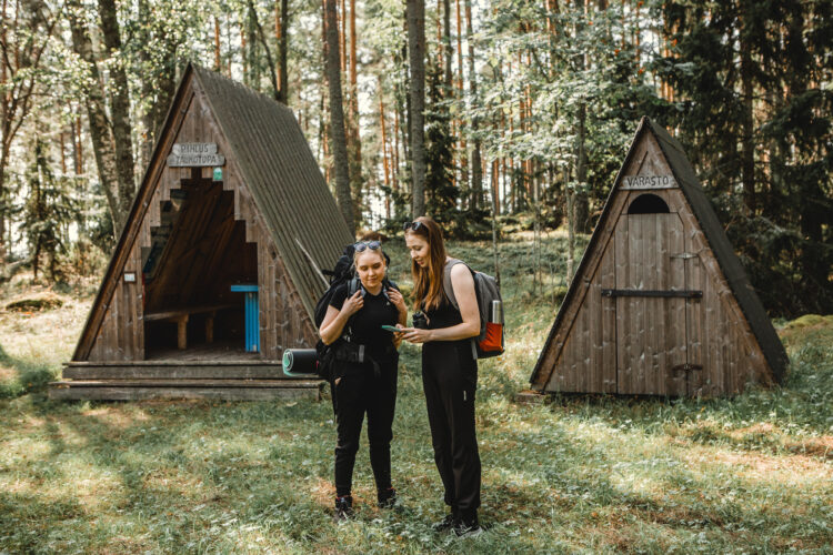 Two hikers looking at a phone in front of a rest stop.