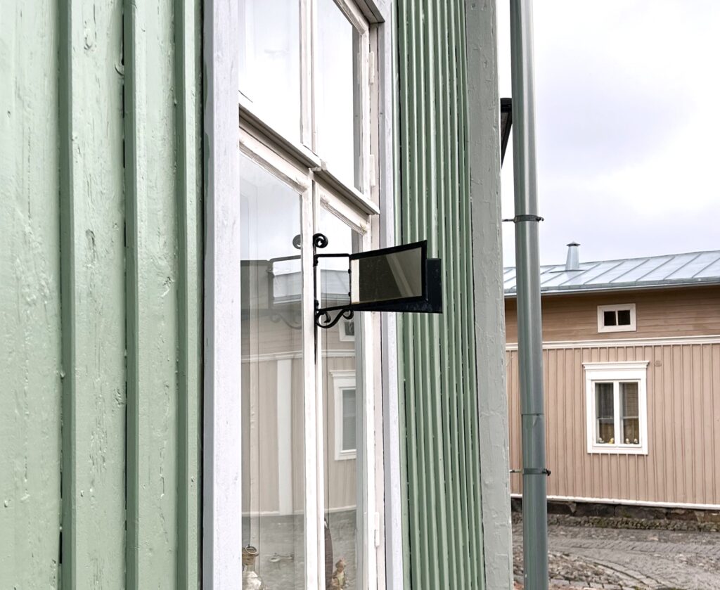 Vanhan Rauman vaaleanvihreään taloon kiinnitetty juorupeili. Juorupeili on kiinnitetty ikkunan eteen ja peilit osoittavat molempiin suuntiin katua.