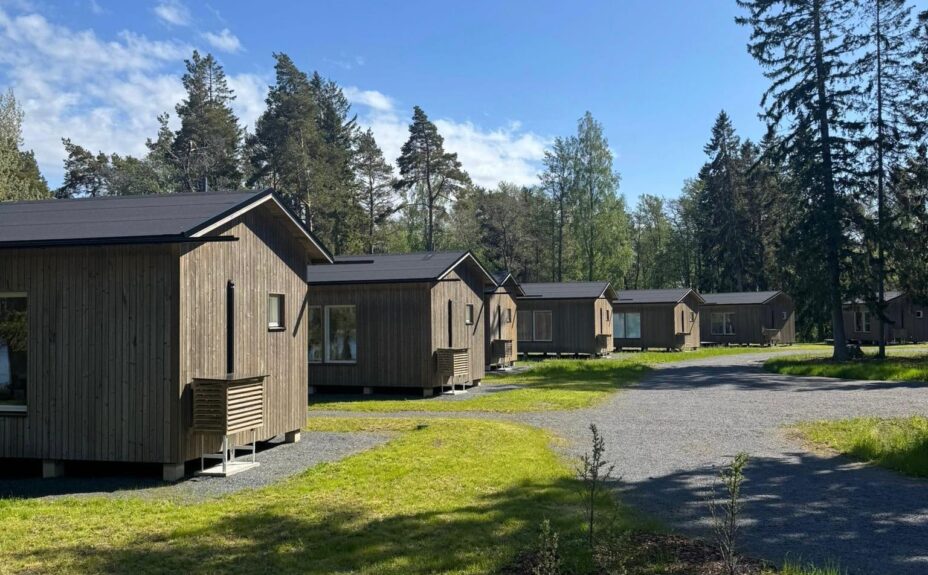 Seitsemän mökkiä rivissä, takana mökki maisema.