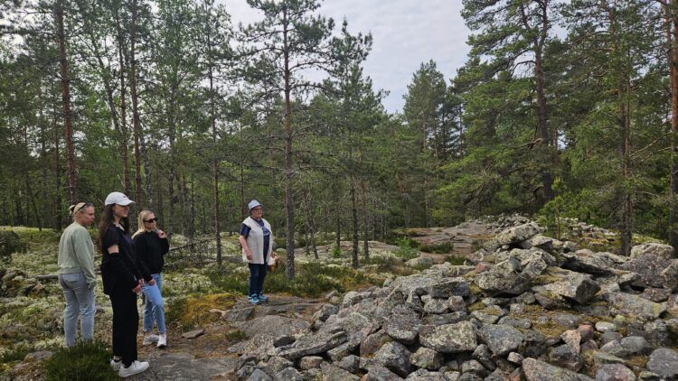 Ihmisiä ja opas katsomassa röykkiötä Sammallahdenmäellä.