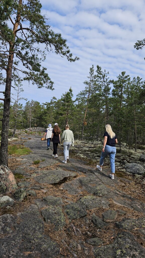 Ihmisiä kävelemässä oppaan perässä Sammallahdenmäen kalliolla.