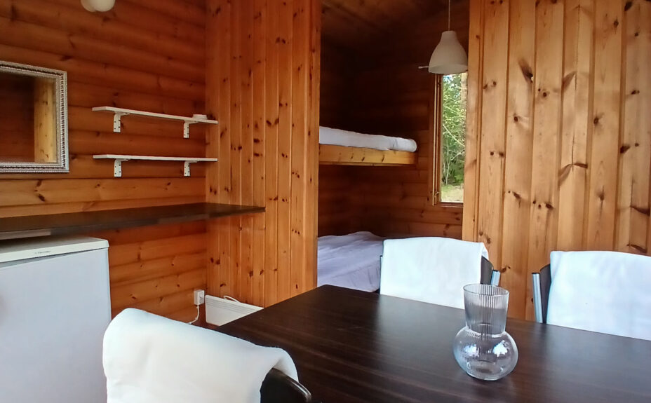 The Karttu cottage form the inside. A dining table with four chairs at front and bunk beds behind.
