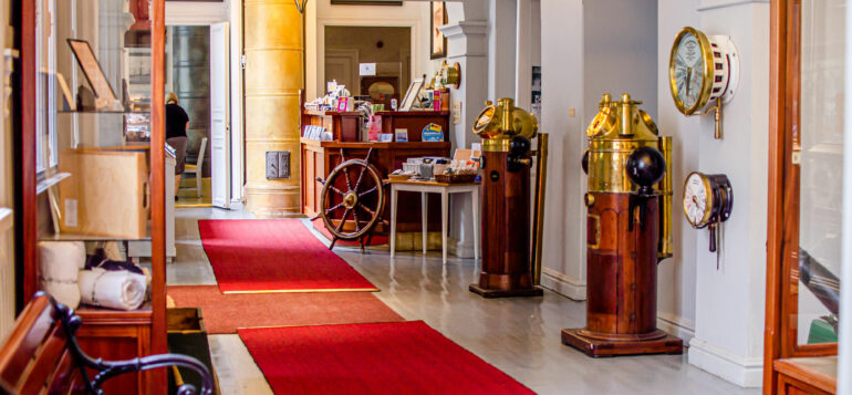 Entrance hall of Rauma Maritime Museum with red carpet and a big ship´s helm.